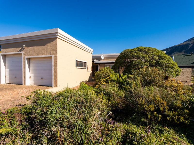 Front view of the property featuring a double garage, paved driveway, and established garden landscaping.