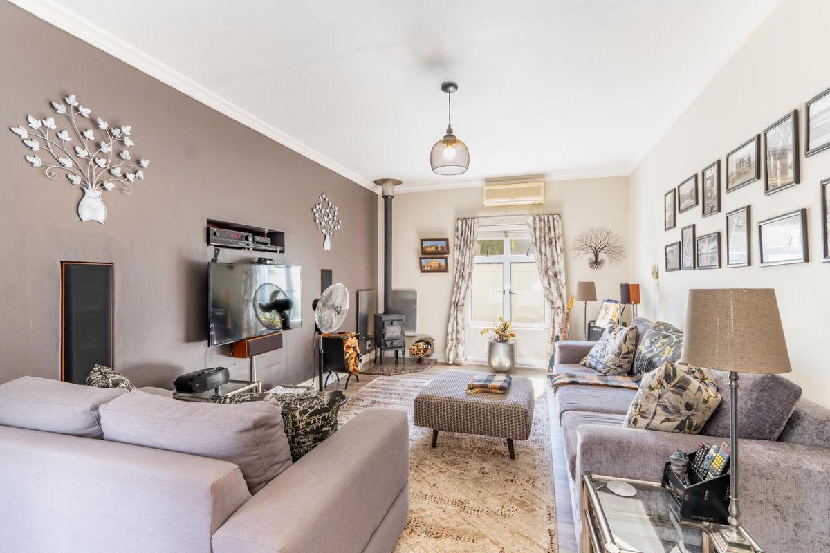 A comfortable living room featuring a wood-burning stove, a recessed wall niche for media, and a wall-mounted split-system air conditioner.