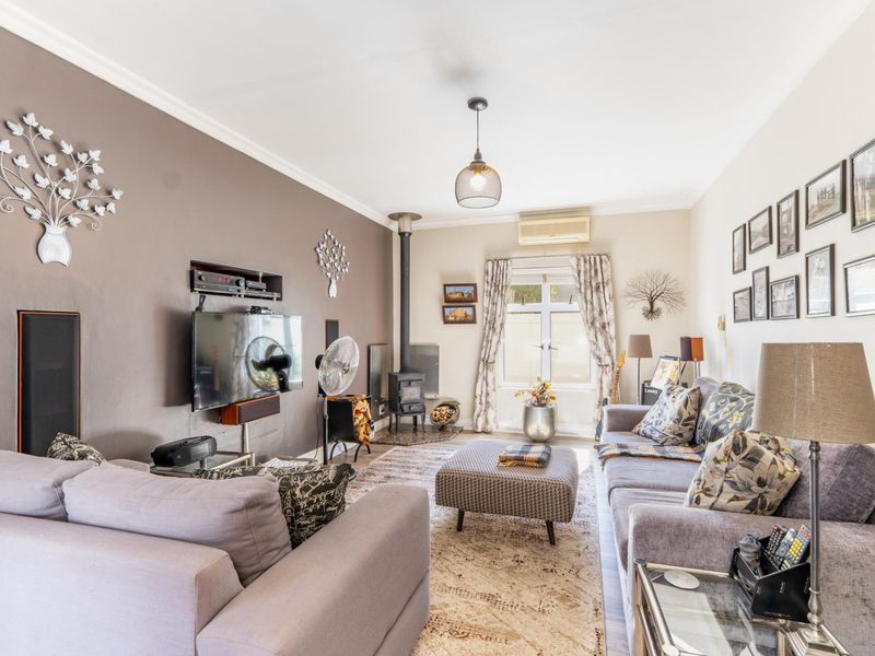 A comfortable living room featuring a wood-burning stove, a recessed wall niche for media, and a wall-mounted split-system air conditioner.