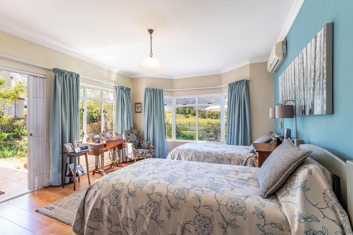 Spacious bedroom featuring hardwood flooring, crown molding, a bay window with garden views, and direct access to an outdoor patio area.
