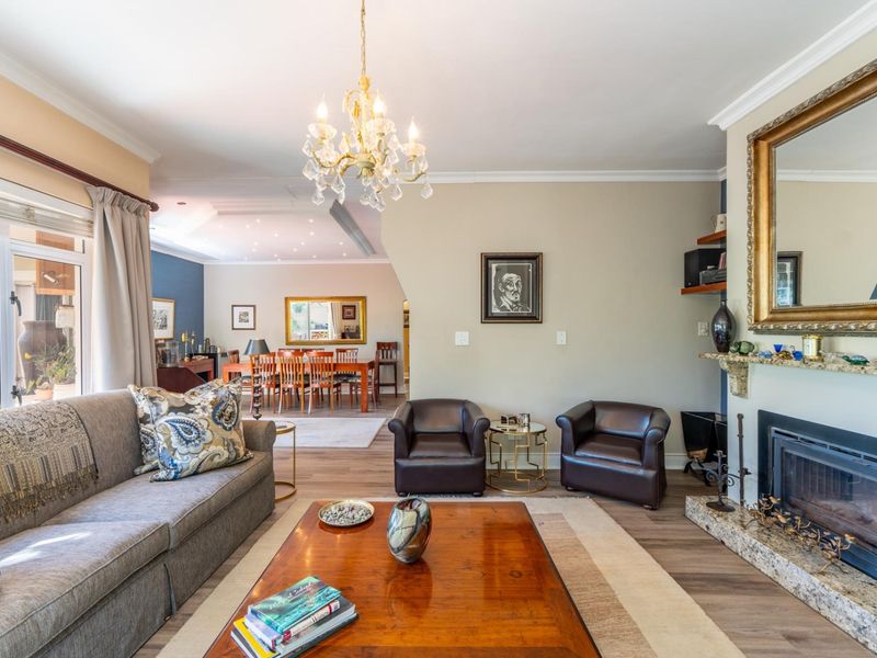 Spacious open-plan living and dining area featuring a fireplace with granite hearth, crown molding, and direct access to an outdoor patio.
