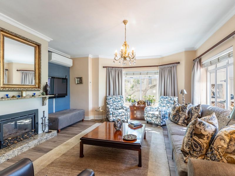 A well-maintained living room featuring a fireplace with a granite surround, laminate flooring, and a split-system air conditioner.
