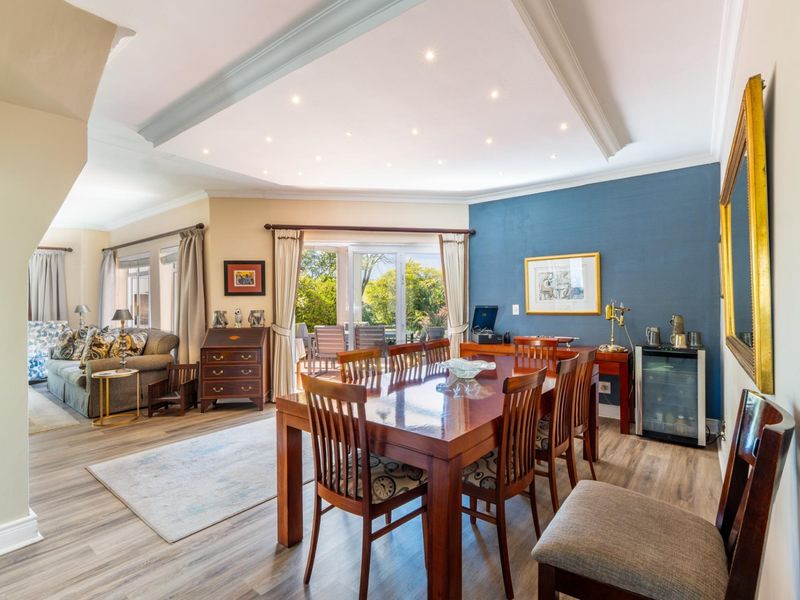 Spacious open-plan dining and living area featuring modern laminate flooring, a stylish tray ceiling with recessed lighting, and direct access to the outdoor patio.