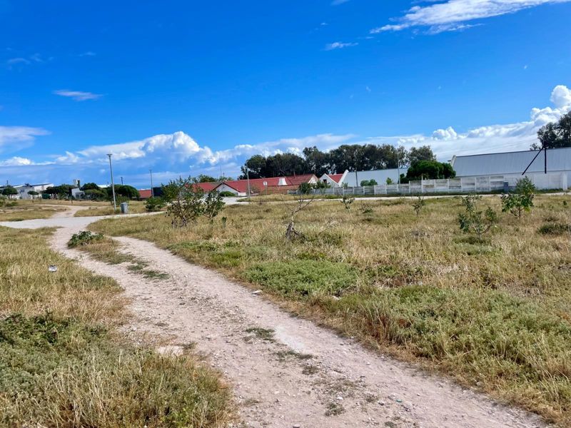 A vacant residential plot featuring an unpaved access path and surrounding neighborhood views, ready for development.