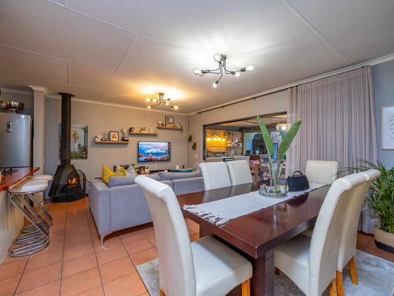 Spacious open-plan living and dining area featuring a cozy fireplace, tiled floors, and seamless flow to the outdoor patio through large sliding doors.