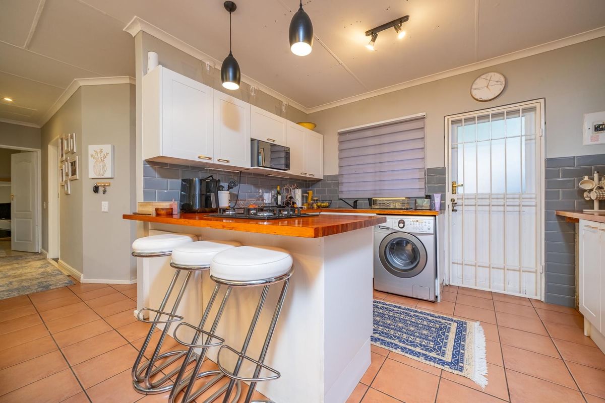Functional kitchen featuring white cabinetry, wooden countertops, gas hob, built-in microwave, and tiled backsplash with direct access to an exterior security door.