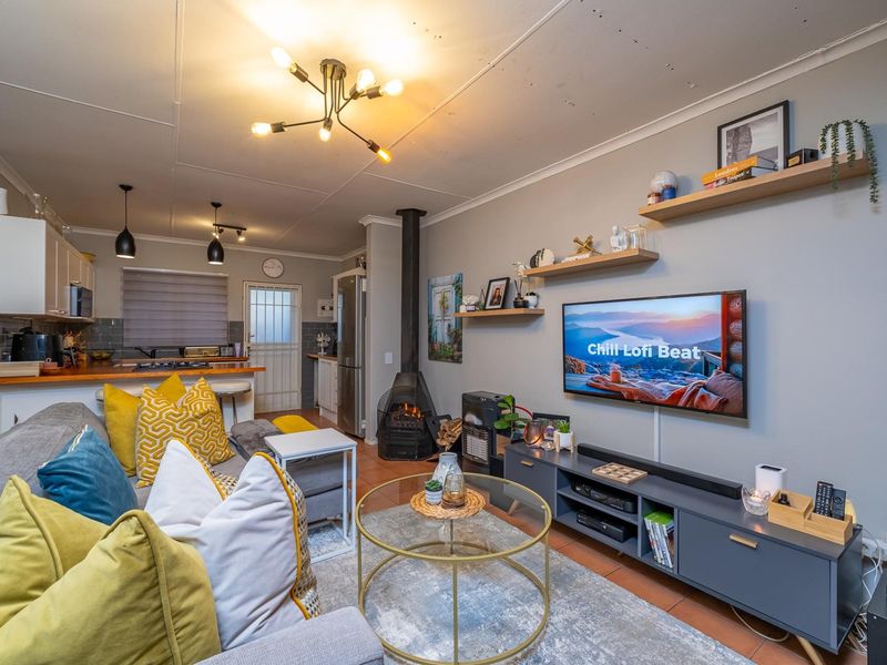 Open-plan living area featuring a modern kitchen with wooden countertops, a cozy freestanding fireplace, and tiled flooring throughout the combined space.