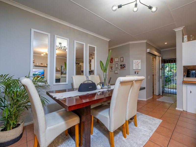 Open plan dining area featuring tiled flooring, neutral walls, and direct access to the exterior through a sliding security gate.