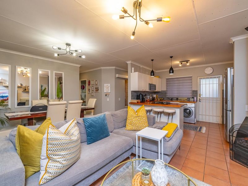 Open-plan living and kitchen area featuring a breakfast bar, tiled flooring, and a cozy fireplace, creating a functional and connected living space.