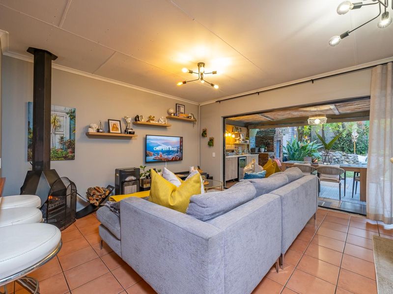 Open-plan living area featuring tiled floors, a modern freestanding fireplace, and seamless flow to the outdoor patio through large sliding glass doors.