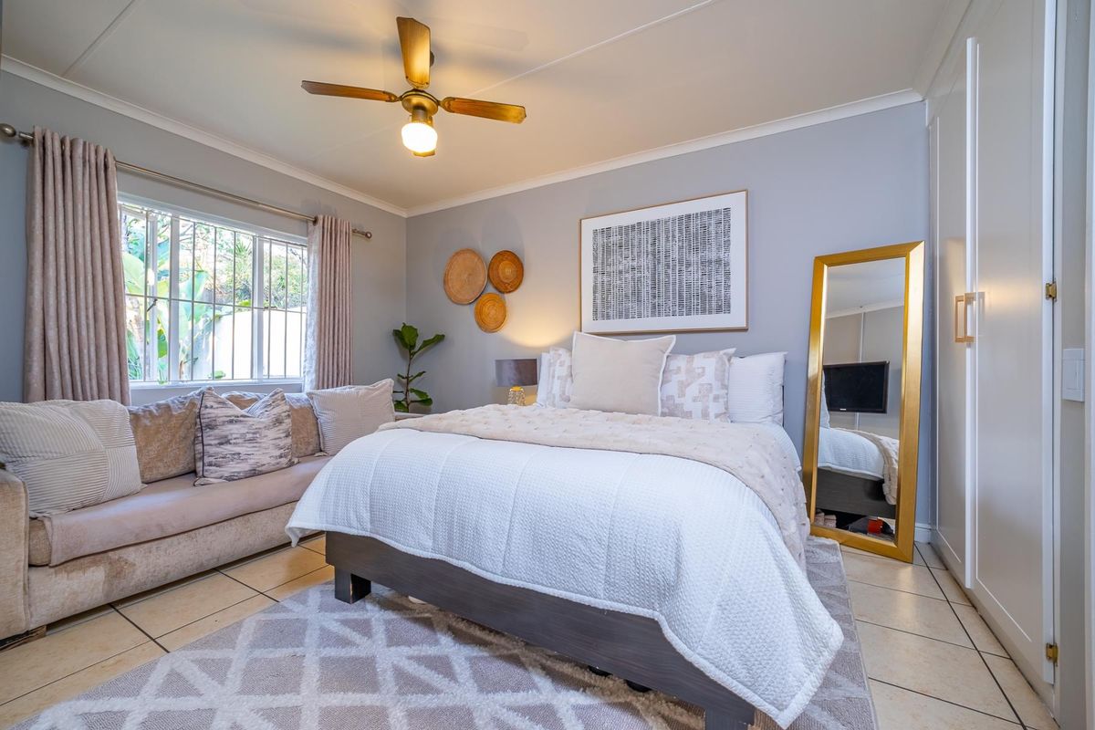 A well-maintained bedroom featuring tiled flooring, a ceiling fan, and a built-in wardrobe, offering a comfortable and functional living space.