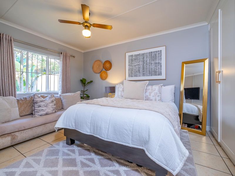 A well-maintained bedroom featuring tiled flooring, a ceiling fan, and a built-in wardrobe, offering a comfortable and functional living space.