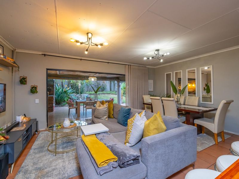 Spacious open-plan living and dining area featuring tiled floors, modern lighting, and large sliding doors providing seamless access to the outdoor patio.