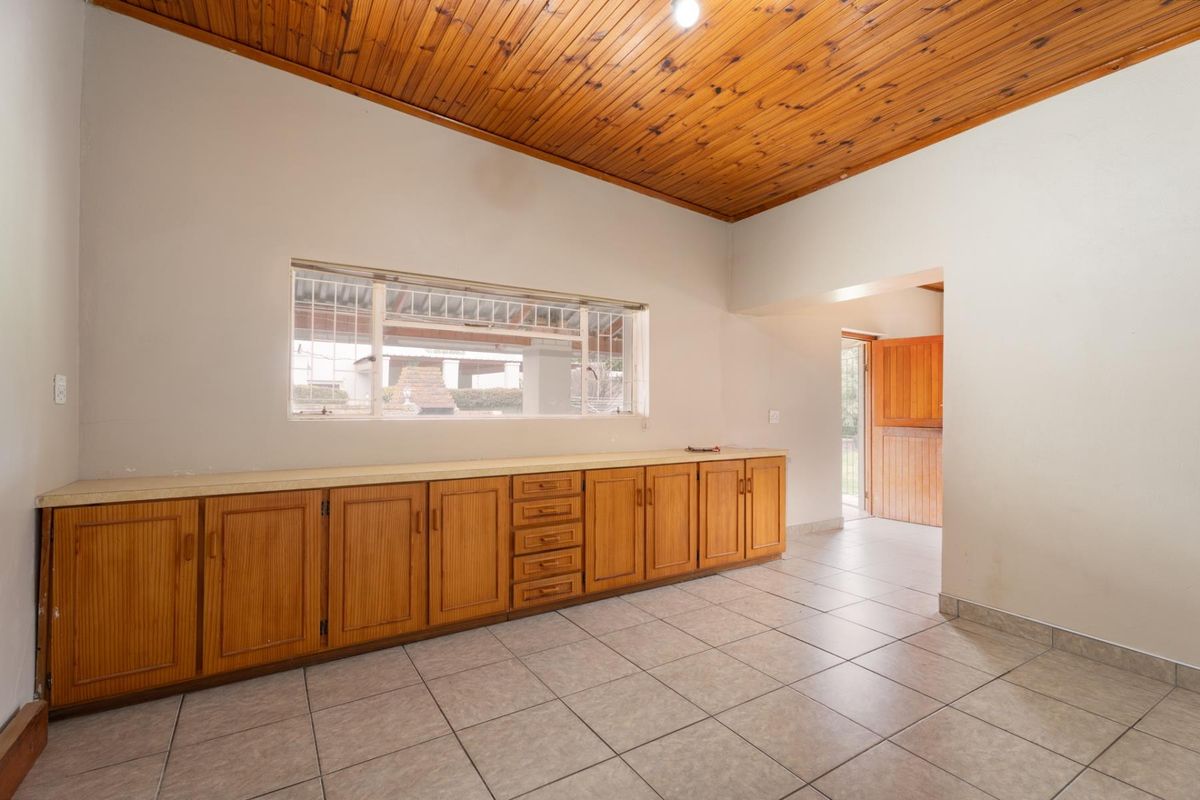 A spacious kitchen area featuring timber ceilings, tiled flooring, and extensive built-in wooden cabinetry with a stable door leading to the exterior.