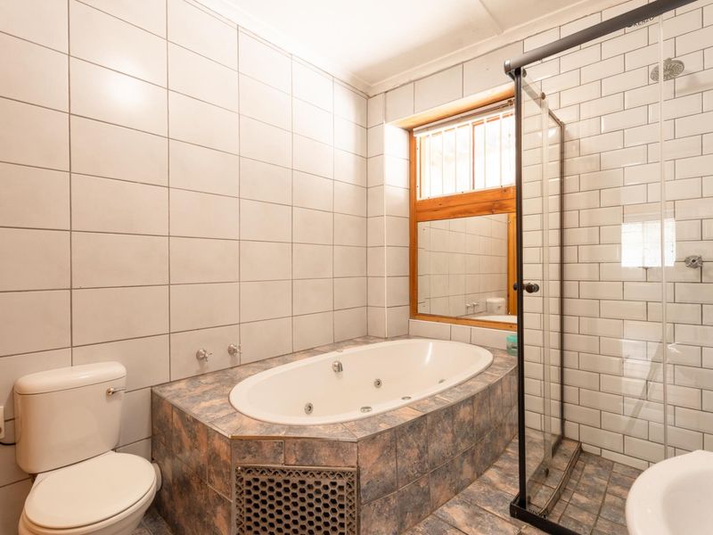 A functional bathroom featuring a built-in bathtub, a separate glass-enclosed shower, and tiled wall finishes.