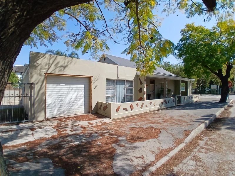 Front exterior view of a single-story house featuring a garage, paved driveway, and low boundary wall with decorative stone accents.
