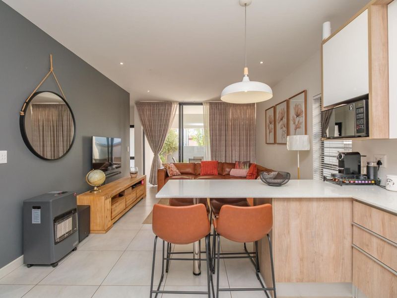 Modern open-plan living area featuring a contemporary kitchen with quartz countertops, tiled flooring, and seamless flow to the outdoor patio through sliding glass doors.