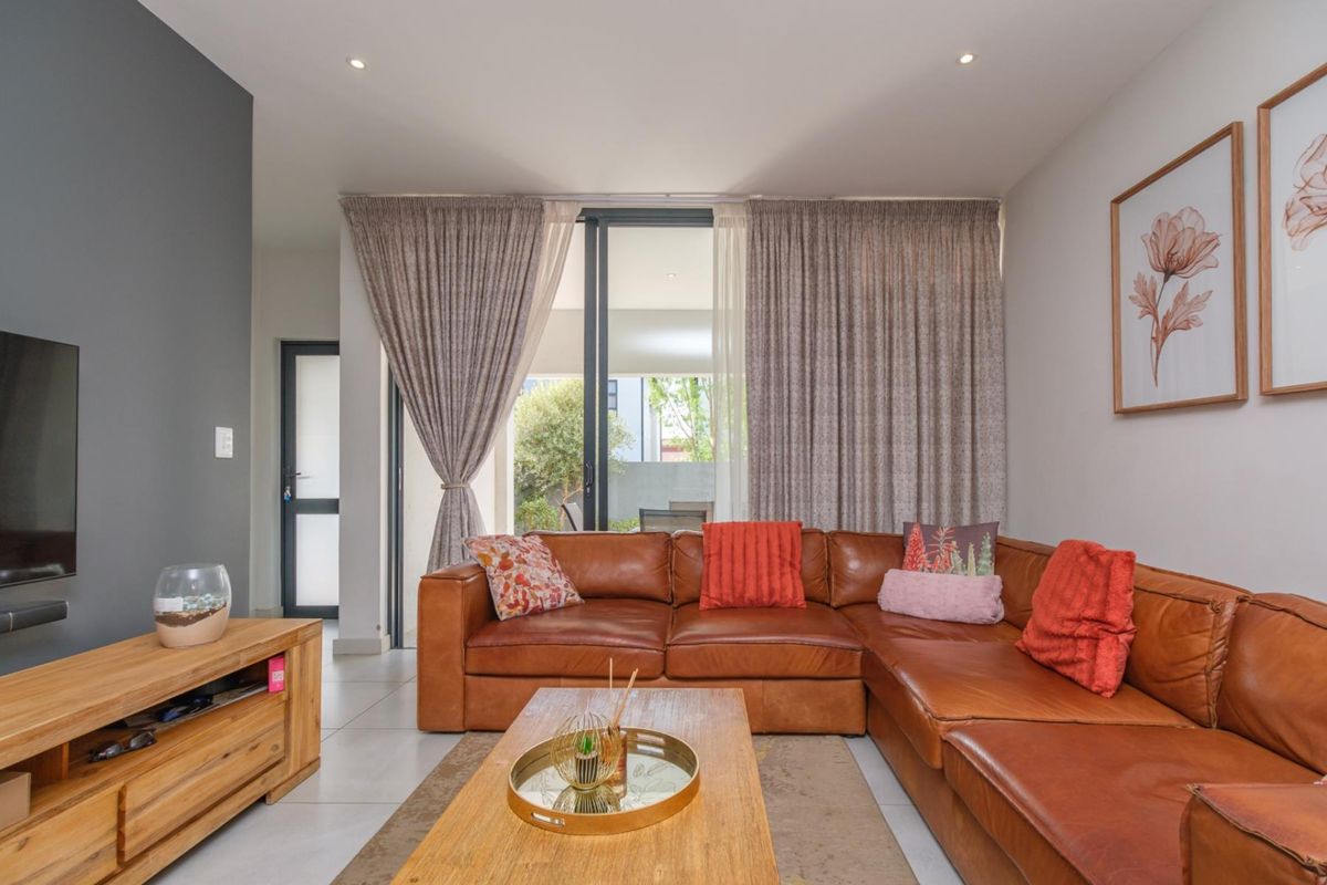 A well-maintained living room featuring tiled flooring, recessed lighting, and a large sliding glass door providing access to the outdoor area.