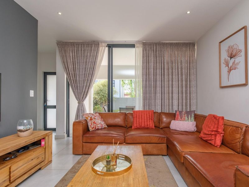 A well-maintained living room featuring tiled flooring, recessed lighting, and a large sliding glass door providing access to the outdoor area.