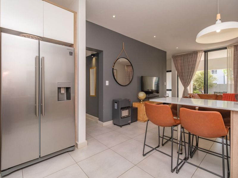 Modern open-plan living area featuring a sleek kitchen with stone countertops, tiled flooring, and seamless flow to the outdoor patio through sliding glass doors.