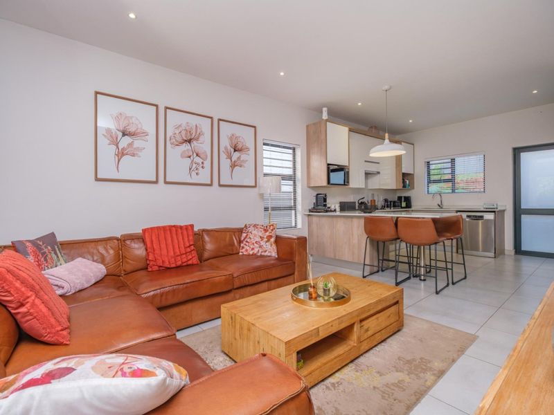 Modern open-plan living area featuring a contemporary kitchen with built-in cabinetry, an island, and seamless flow into the comfortable lounge space.