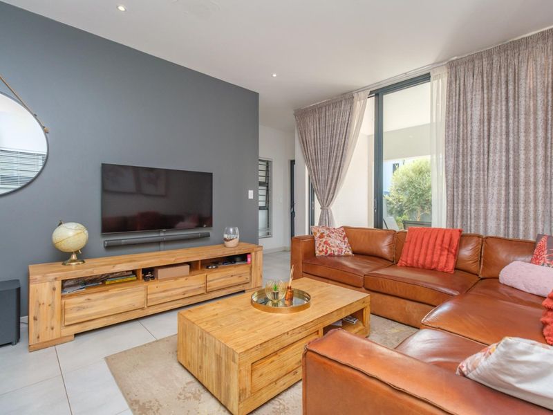 A well-maintained living room featuring a dark accent wall, tiled flooring, and large sliding glass doors that provide natural light and access to outdoors.