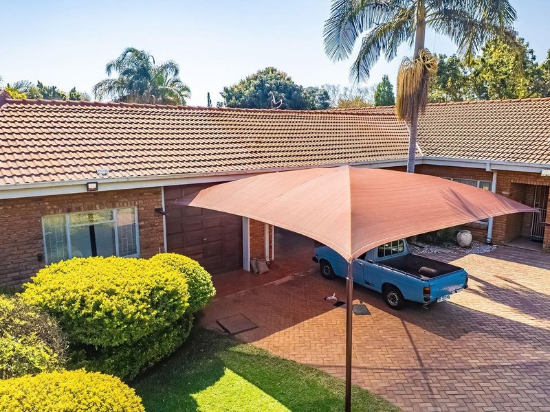 Front exterior view of the house featuring a brick facade, tiled roof, and a paved driveway with a shade sail structure.