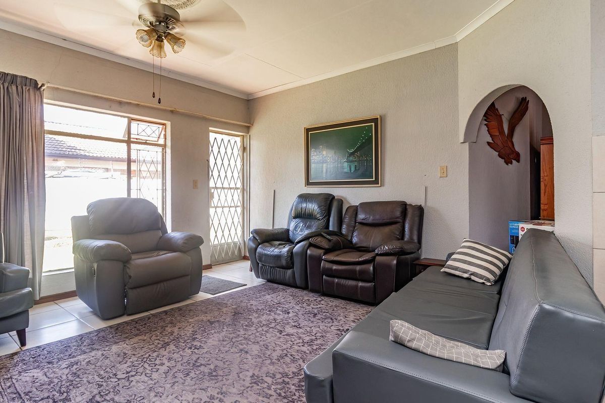 A spacious living room featuring tiled flooring, a ceiling fan, and an arched entryway leading to adjacent areas.