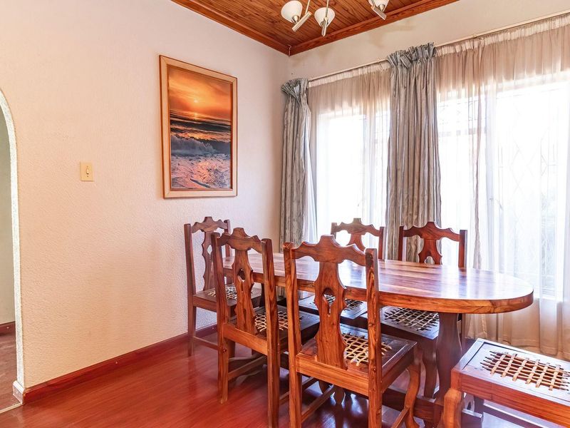 A dining room featuring timber ceiling paneling, laminate flooring, and an arched entryway leading to an adjacent space.