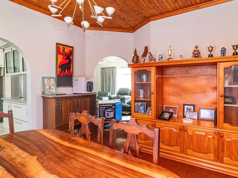 Dining room featuring a timber ceiling and arched entryways leading to adjacent living and kitchen areas.
