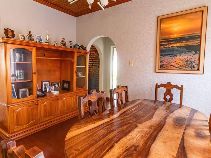A dining room featuring a timber ceiling, laminate flooring, and a classic arched doorway leading to an adjacent space.