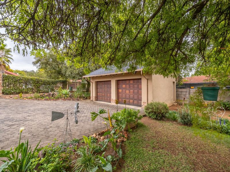 A detached double garage with a paved driveway and landscaped garden surroundings.