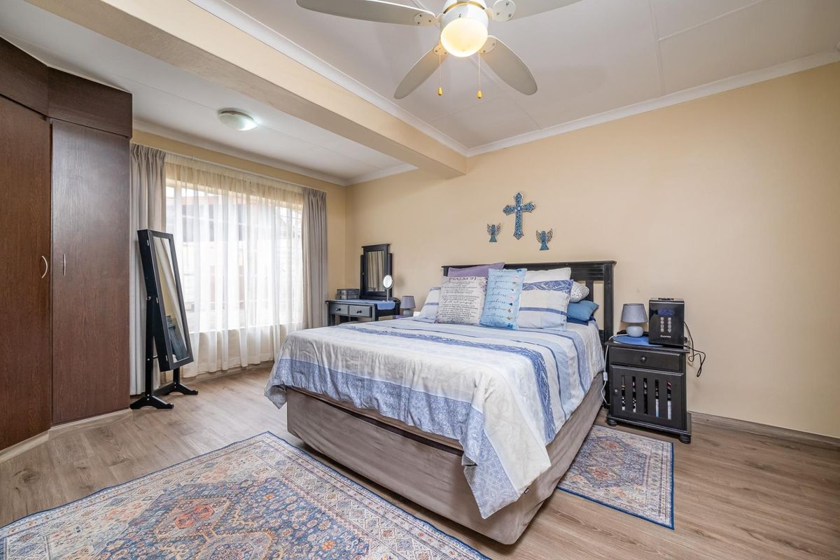 A well-maintained bedroom featuring laminate flooring, a ceiling fan, and a built-in wardrobe with neutral wall finishes.