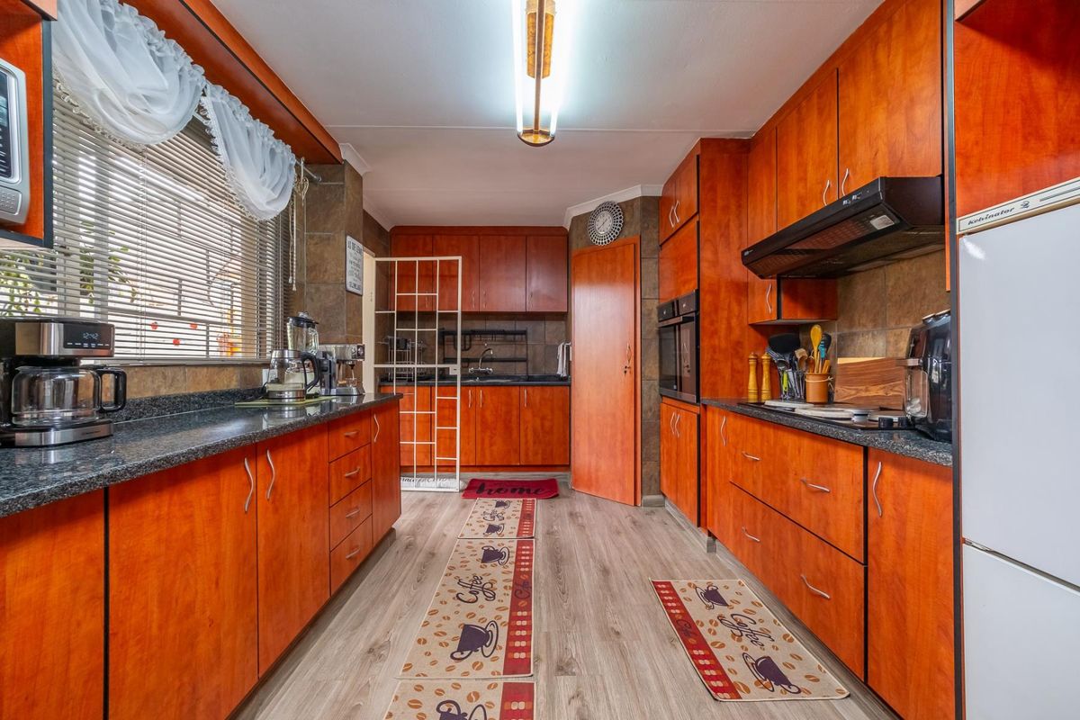 A functional kitchen featuring warm-toned laminate cabinetry, granite countertops, built-in oven, extractor fan, and durable laminate flooring.