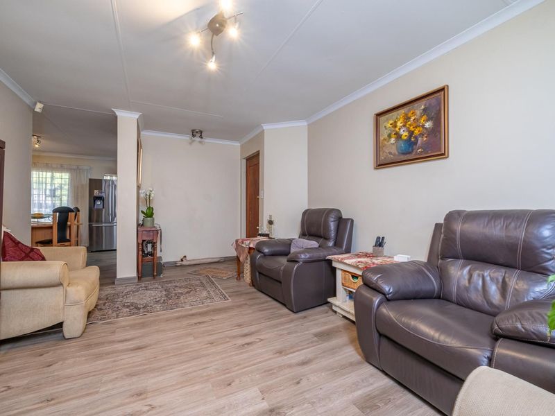 Open-plan living area featuring durable laminate flooring and coved ceilings, flowing seamlessly into a functional kitchen space.