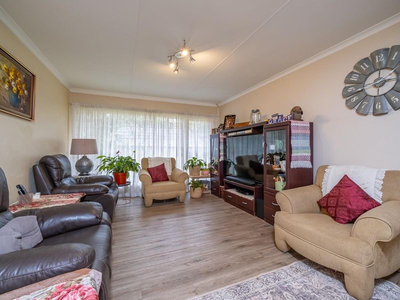 A well-maintained living room featuring laminate flooring, cove ceiling detailing, and a central spotlight fixture, providing a comfortable and functional living space.