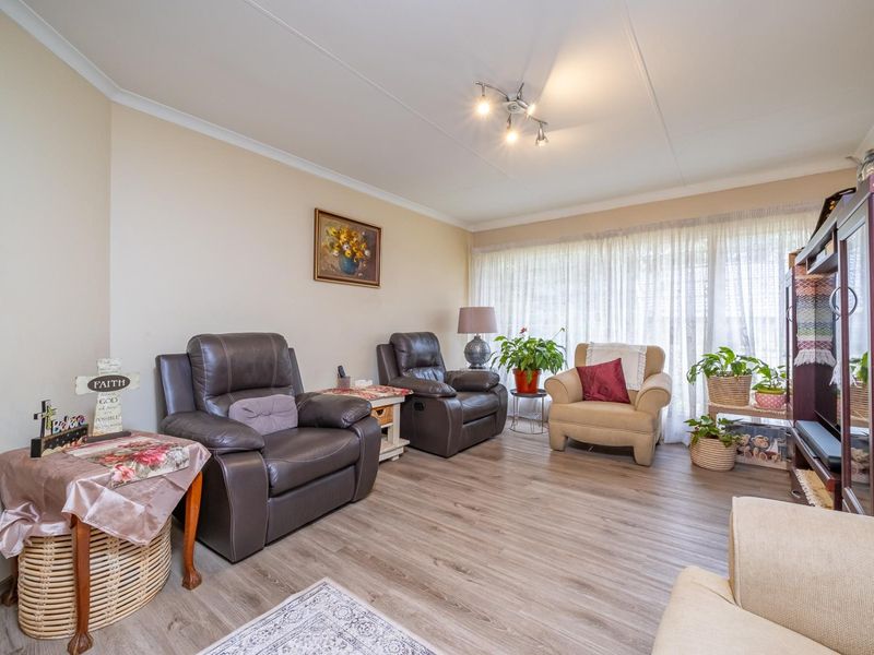 A comfortable living room featuring durable laminate flooring, neutral wall finishes, and modern track lighting, providing a functional and inviting space.
