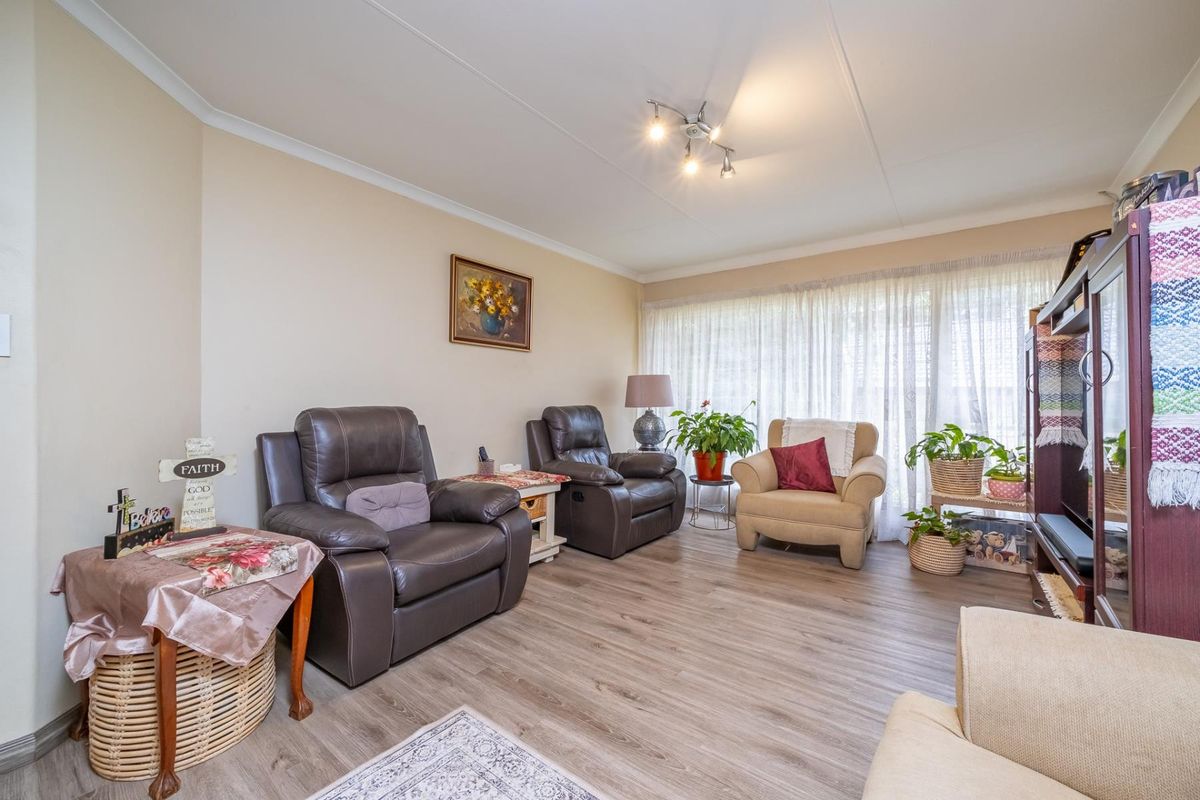 A comfortable living room featuring durable laminate flooring, neutral wall finishes, and modern track lighting, providing a functional and inviting space.