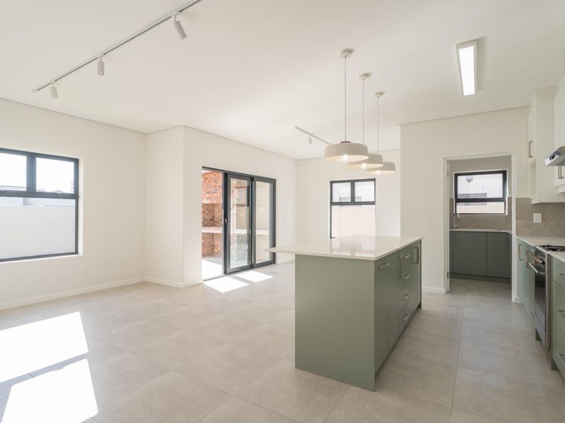 Modern open-plan kitchen and living area featuring a central island, sleek cabinetry, high-quality finishes, and seamless access to the outdoor patio.