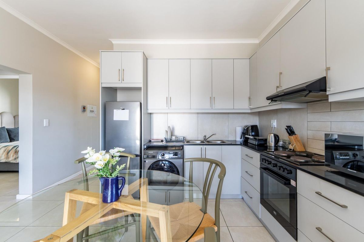 Modern kitchen featuring sleek grey cabinetry, dark countertops, integrated appliances, and tiled flooring, offering a clean and functional culinary space.