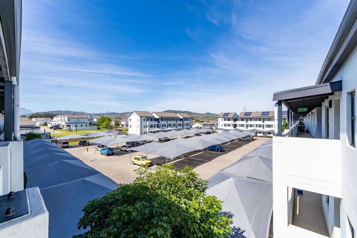 Elevated view of the apartment complex parking area featuring multiple shade sail carports and surrounding residential buildings.