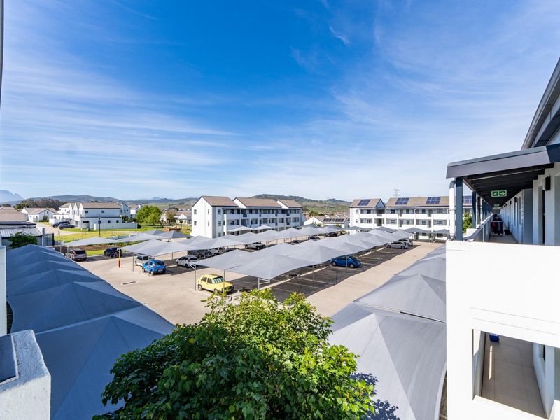 Elevated view of the apartment complex parking area featuring multiple shade sail carports and surrounding residential buildings.