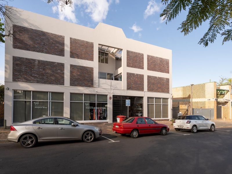 Front exterior view of a multi-story apartment building featuring a commercial storefront on the ground level with large glass windows and brick facade accents.