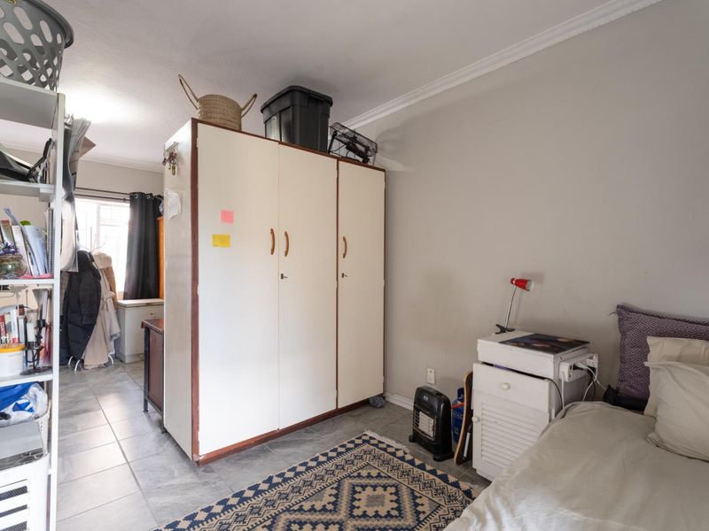 A bedroom featuring tiled flooring, a built-in wardrobe, and decorative cornice detailing.