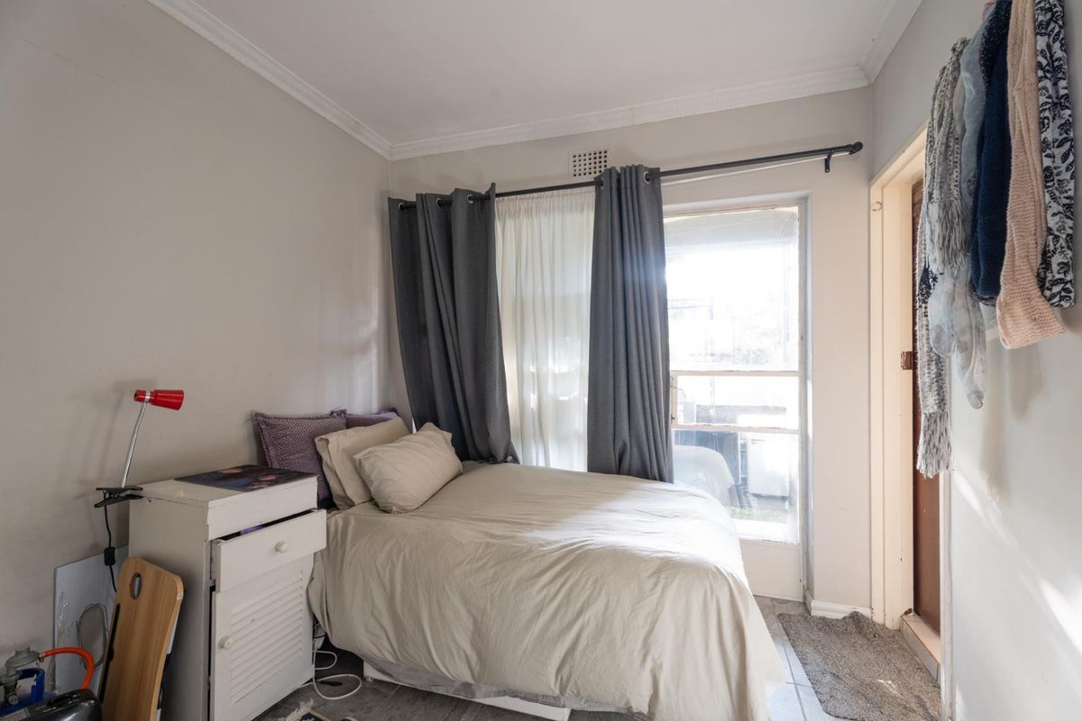 A compact bedroom featuring tiled flooring, crown molding, and a glass door providing natural light and access to an outdoor area.