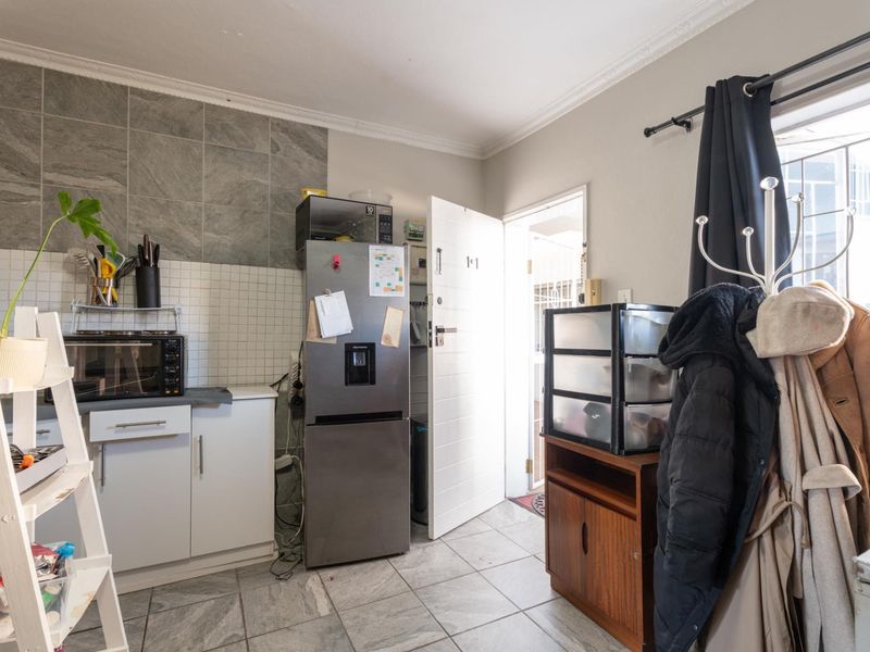 A functional kitchen area featuring tiled flooring, a tiled backsplash, and built-in cabinetry with direct access to an exterior door.