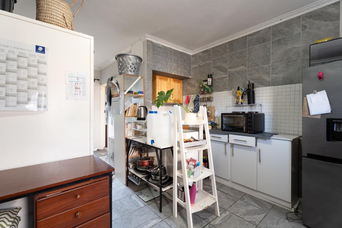 A functional kitchen area featuring tiled flooring, a tiled backsplash, and built-in cabinetry, providing a practical space for food preparation and storage.