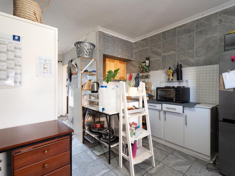 A functional kitchen area featuring tiled flooring, a tiled backsplash, and built-in cabinetry, providing a practical space for food preparation and storage.