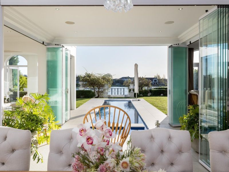 Elegant open-plan living area featuring seamless indoor-outdoor flow through stacking glass doors to a private swimming pool and landscaped garden.