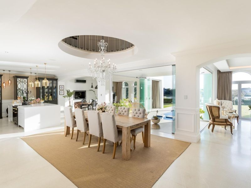 Spacious open-plan living and dining area featuring a modern kitchen, elegant ceiling detail, and seamless flow to the outdoor patio through stacking glass doors.